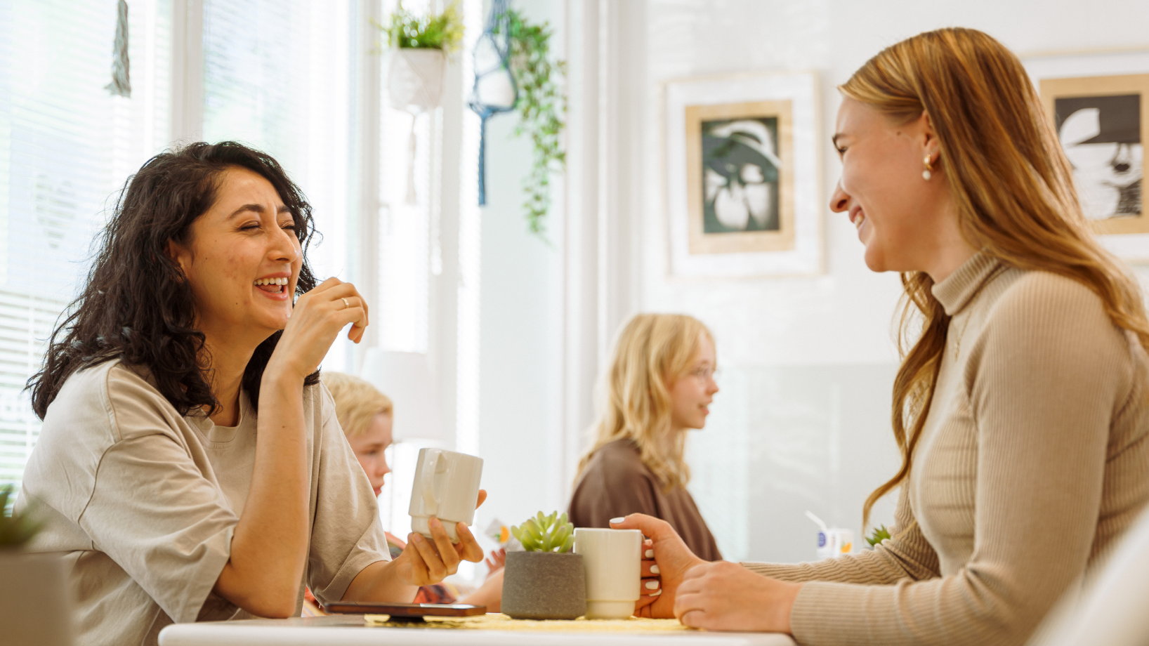 kaksi nuorta naista istuu kahvilassa ja nauraa