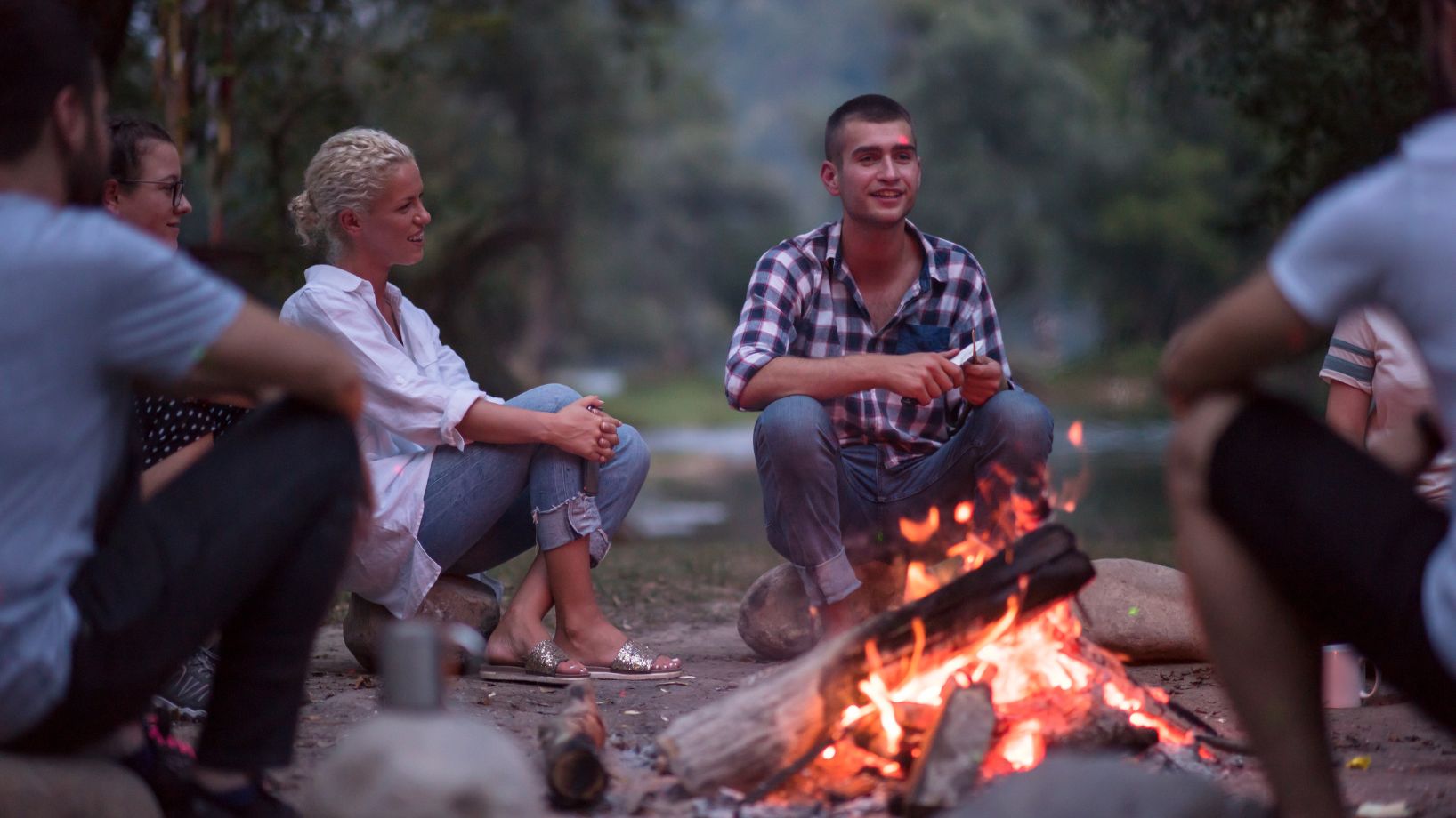 Ihmiset juttelevat nuotion äärellä